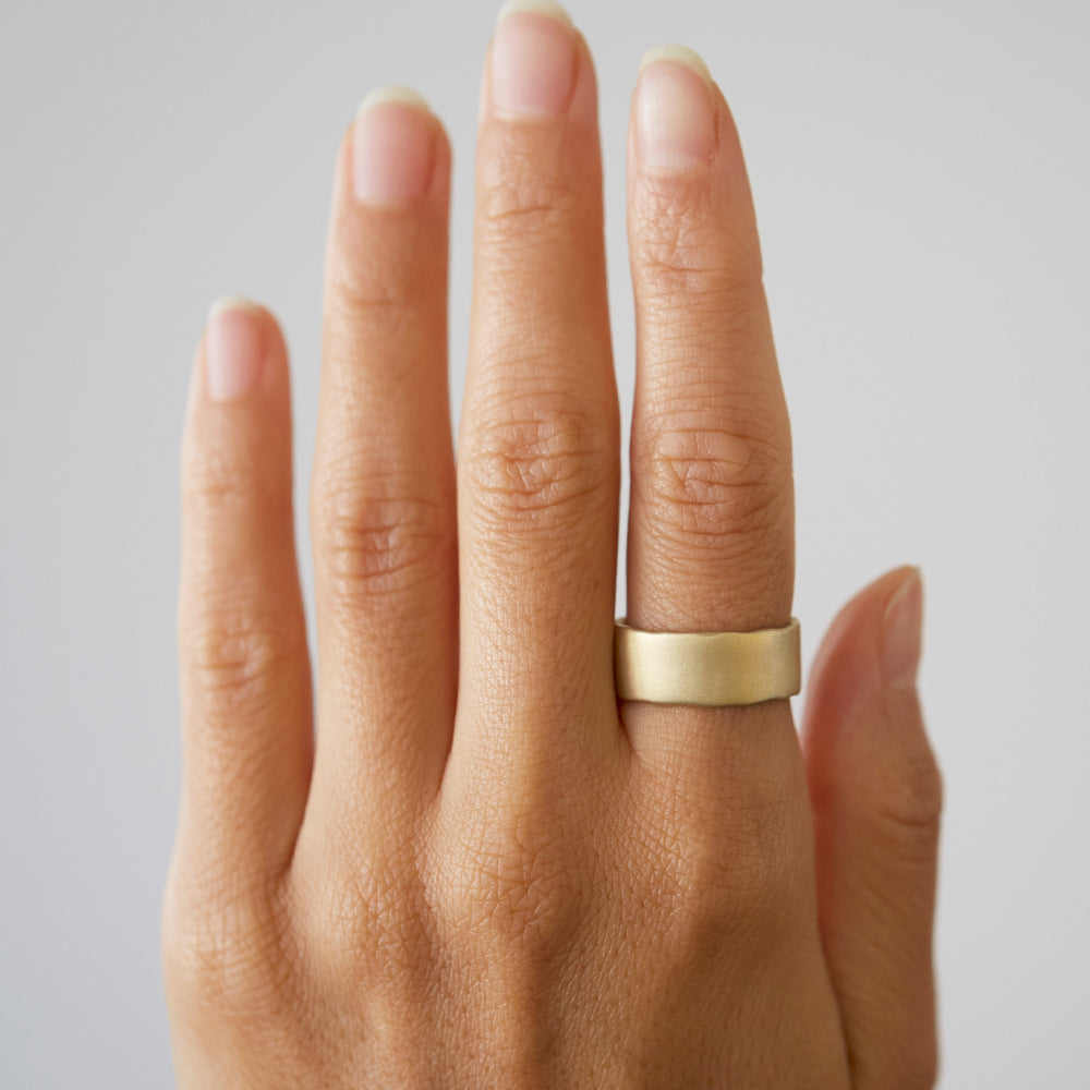Torn Paper Band P-R15 shiny gold ring band on hand, slim hammered texture in warm light