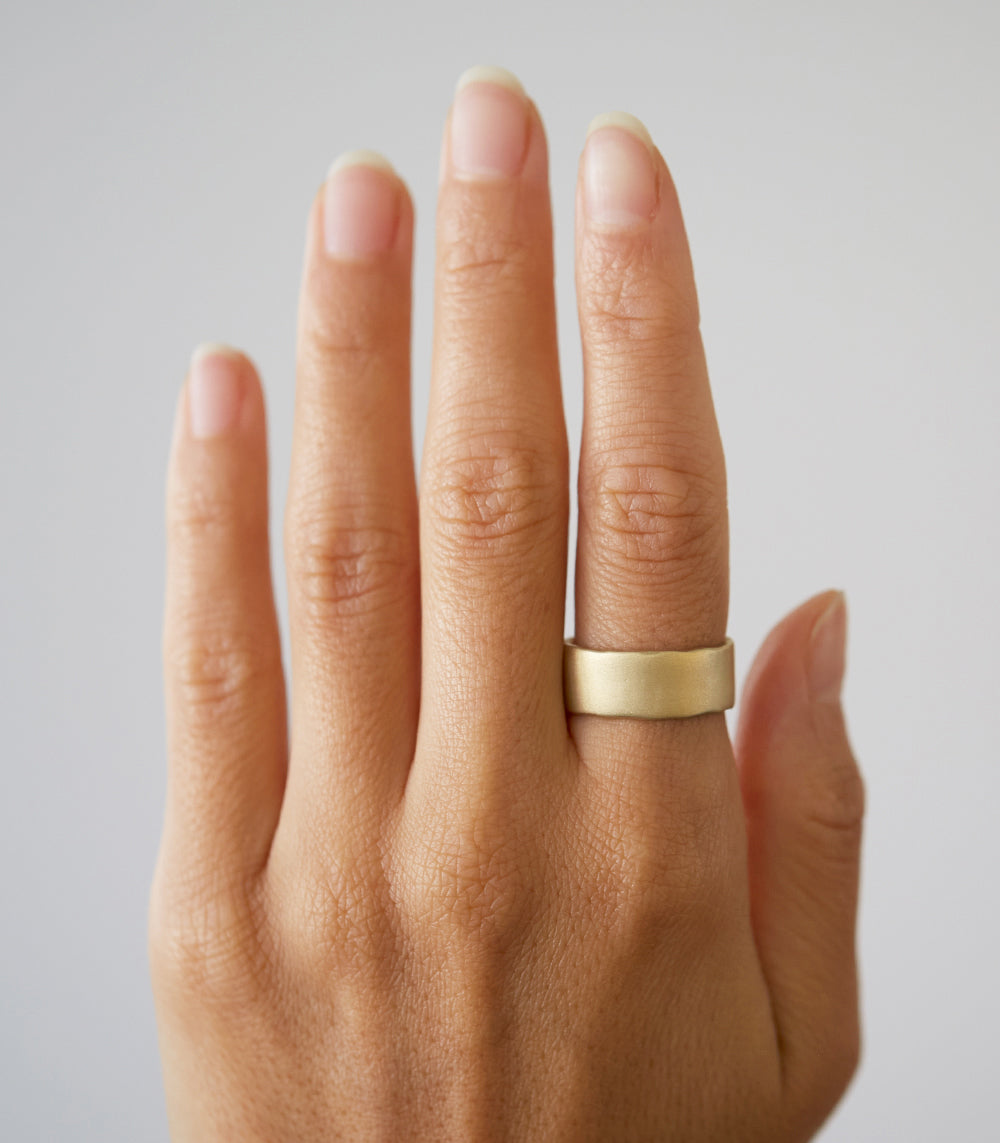 Torn Paper Band P-R15 shiny gold ring band on hand, slim hammered texture in warm light