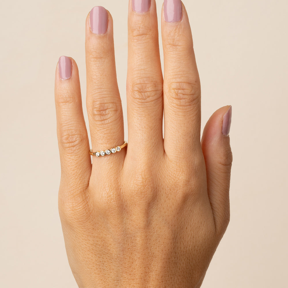 Diamond Bezels EB-R17-D5 diamond band in 14K yellow gold with shiny bezel-set stones on finger