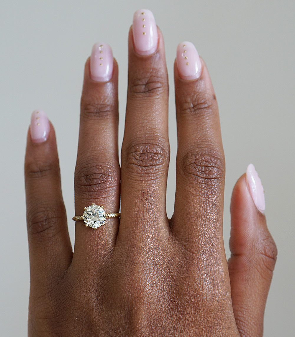 Evangeline by SK-R92-OEC engagement ring in gold with a round diamond center stone on a hand