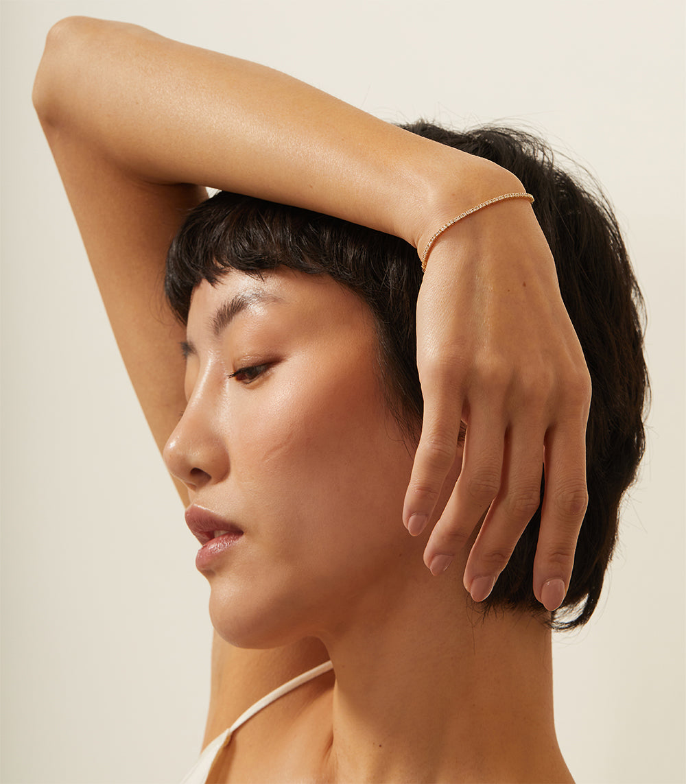 The Hills CC-DB1 understated thin gold bracelet on a model’s wrist, soft studio lighting.